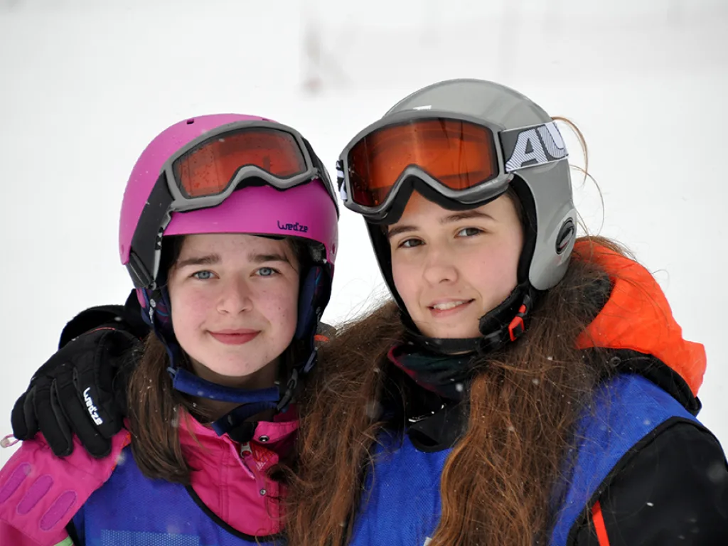 Zwei Jugendliche mit Helm und Skibrille lachen in die Kamera.